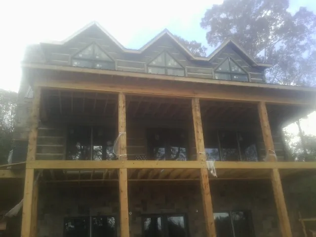 Dormers and porch framing on a large log home under construction — Roof Coating work by our crew in Dallas